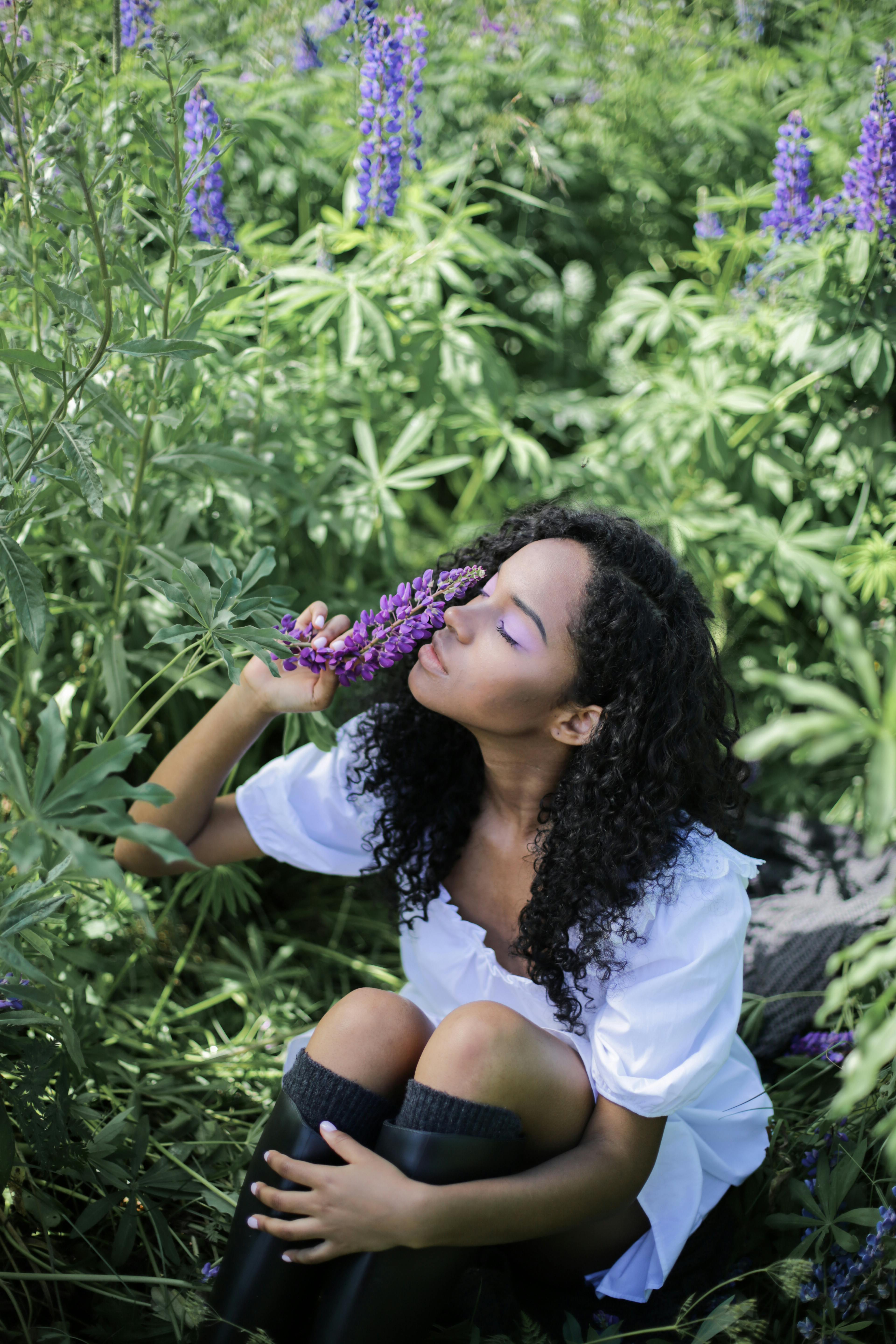 Young woman enjoying the vibrant beauty of purple lupines in nature.