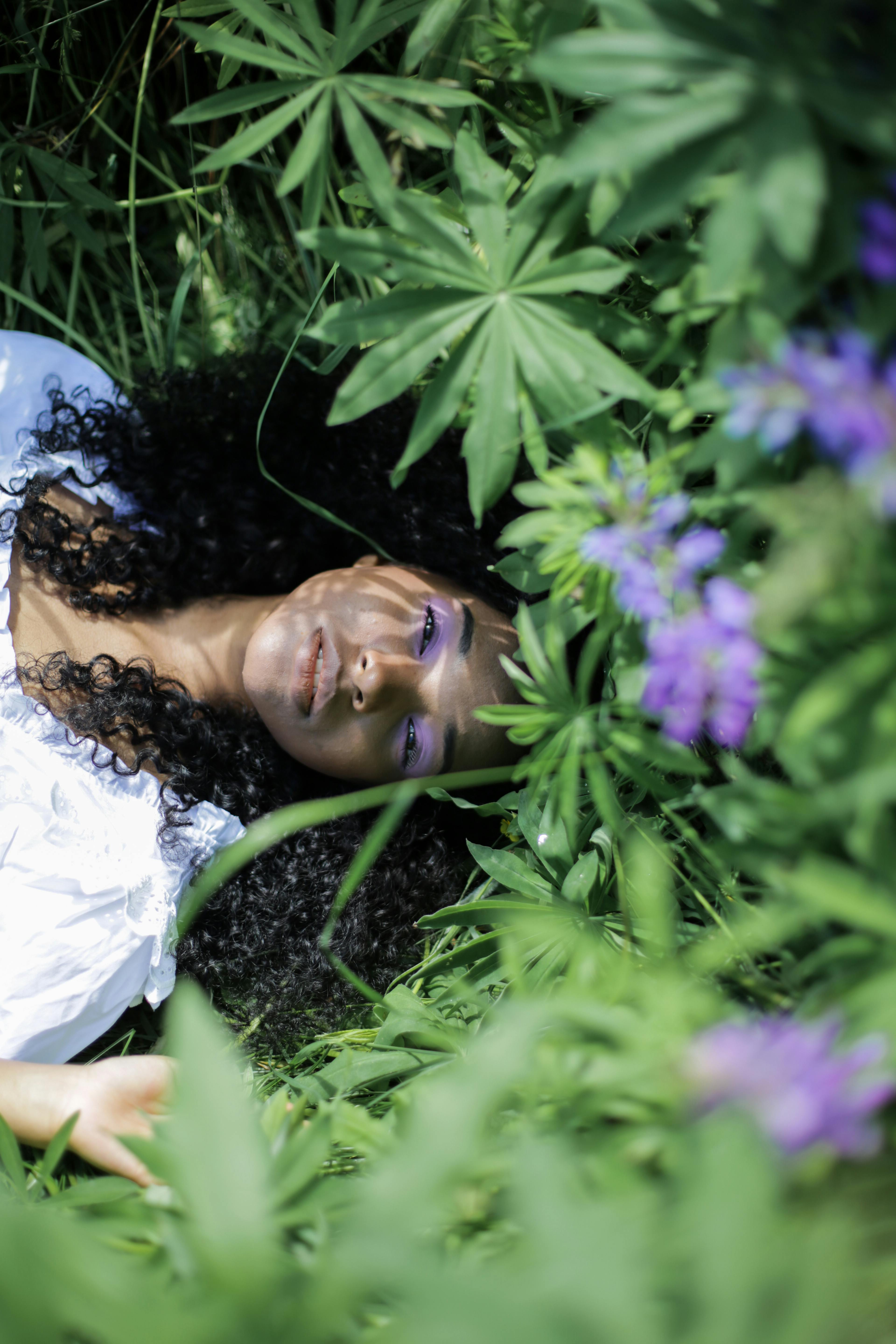 Serene portrait of a woman surrounded by lush lupine flowers and greenery.