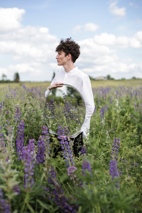 Woman in White Long Sleeve Shirt Standing on Purple Flower Field