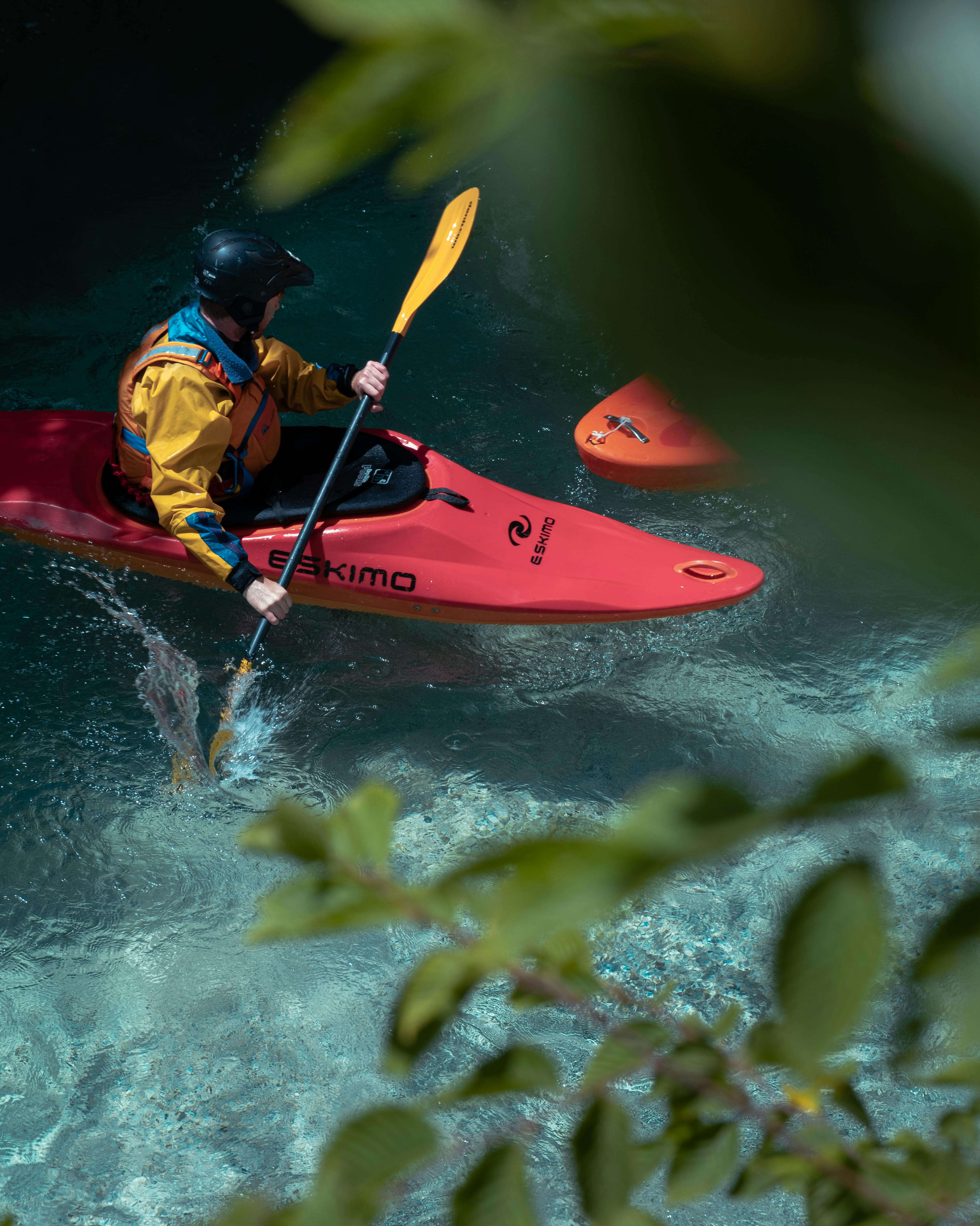 Kayaker paddling through the clear waters of Soča River, Slovenia, surrounded by pristine nature.