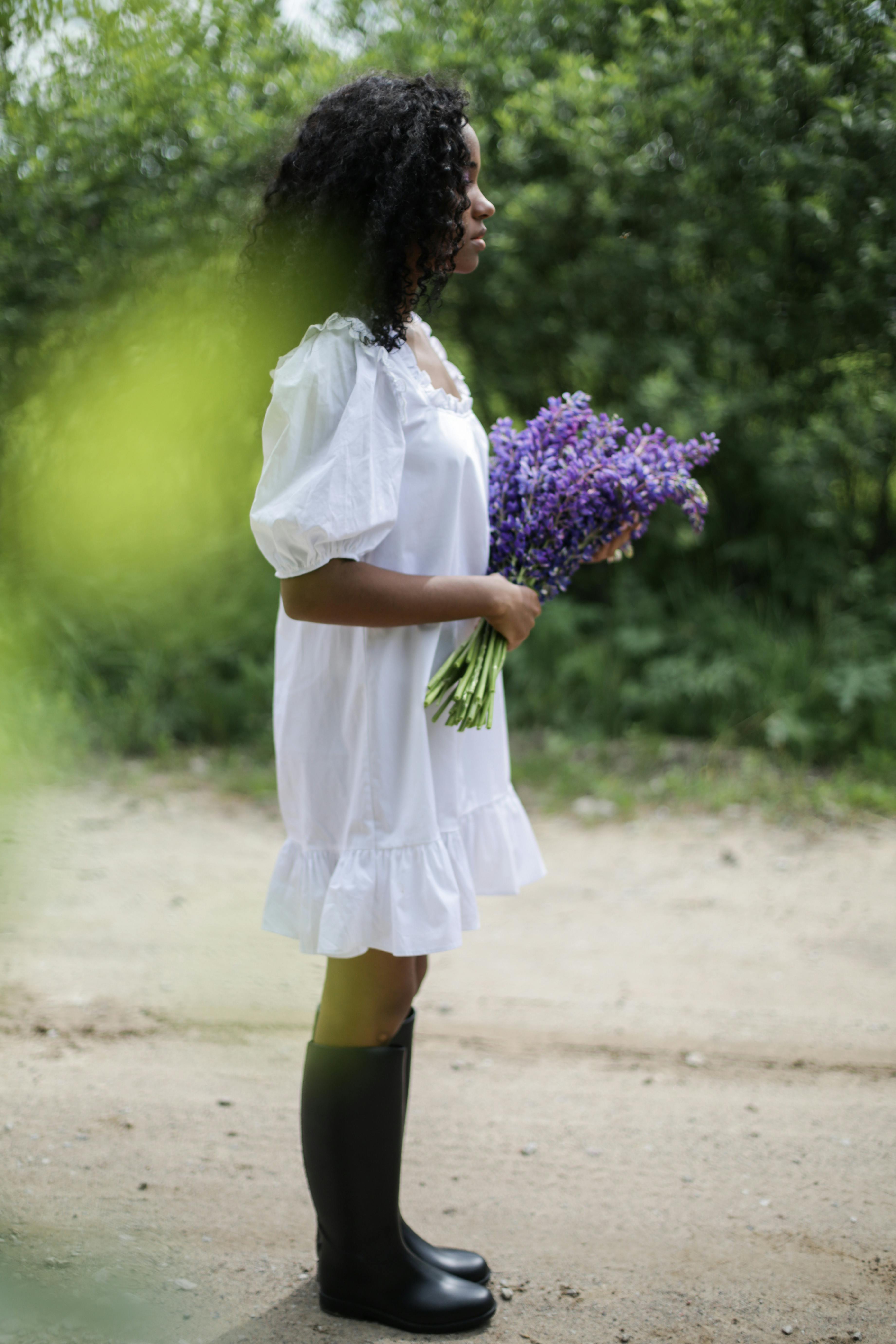 woman-in-white-dress-holding-purple-flowers-free-stock-photo