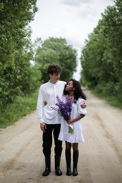 Man and Woman Holding Hands While Walking on Road