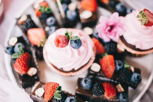 Close-up of cupcakes with raspberries, blueberries, and strawberries for a sweet dessert treat.