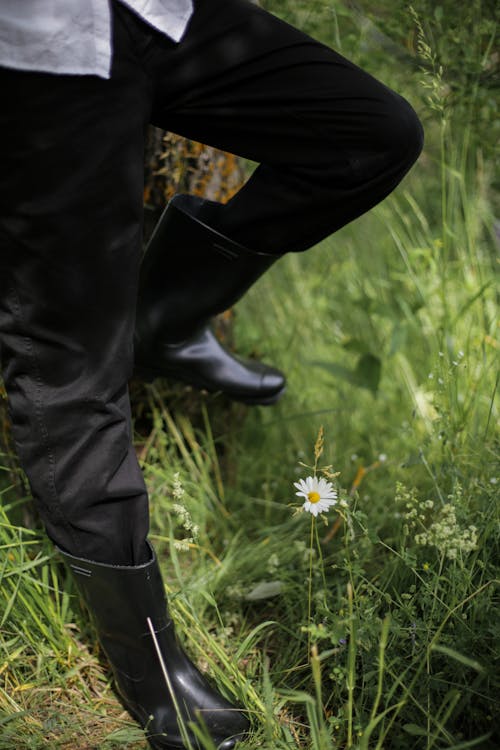 Person in Black Pants and Black Leather Boots Standing on Green Grass Field