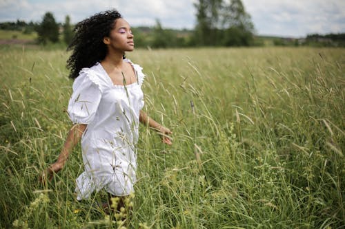 Girl in White Dress Standing on Green Grass Field