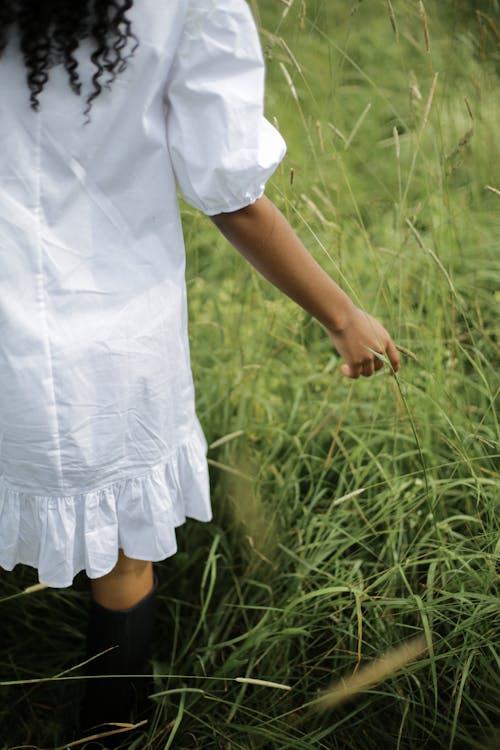Girl in White Dress Standing on Green Grass Field