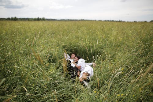 Free Woman in White Long Sleeve Shirt Lying on Green Grass Field Stock Photo