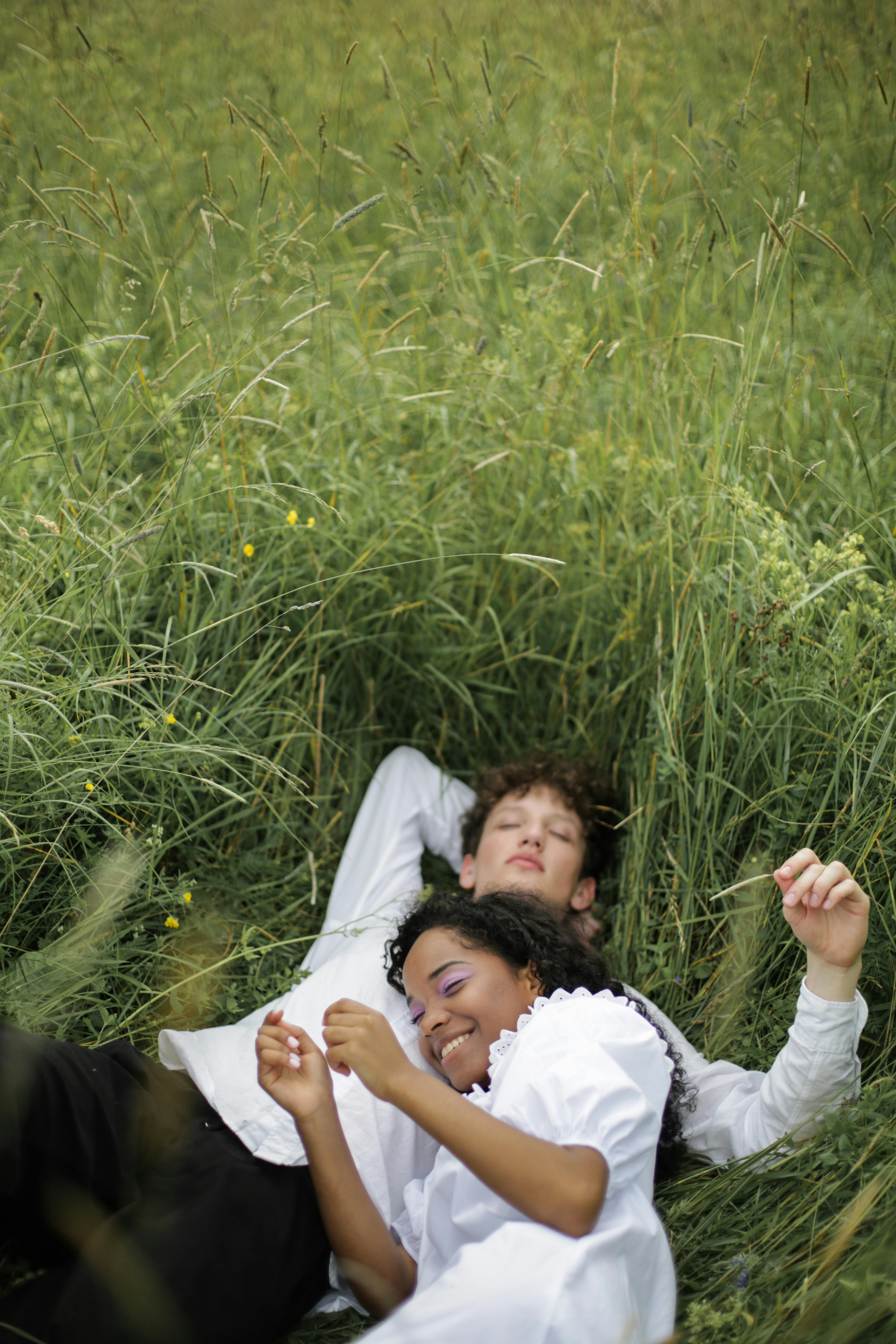 man and woman lying on green grass field