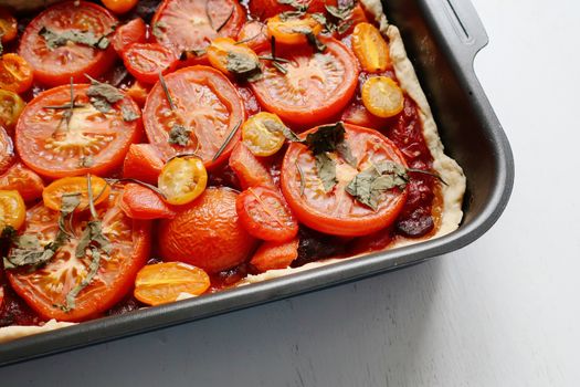 Delicious tomato pie topped with fresh herbs in a baking dish, perfect for a savory meal.
