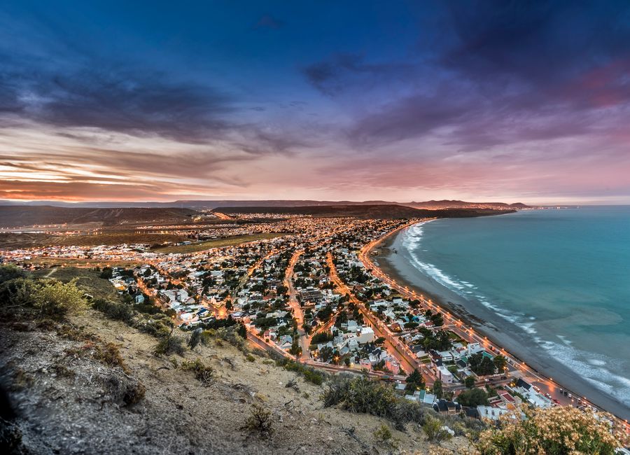 Stunning aerial view of Rada Tilly, Argentina, showcasing the coastline and vibrant sunset sky.
