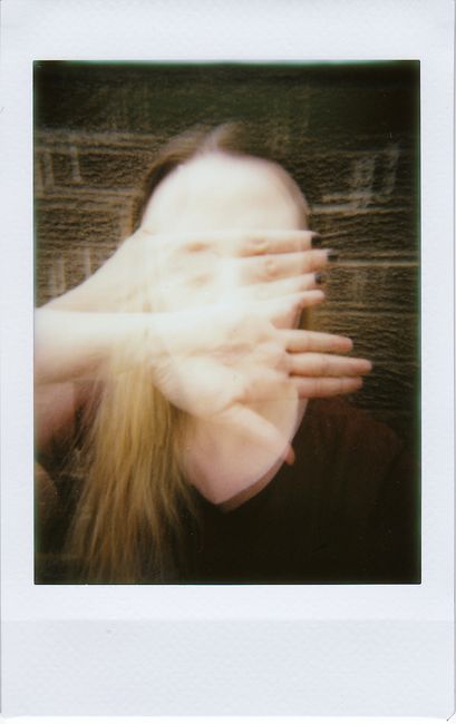 Blurred artistic portrait of a woman with hands covering face, embodying mystery and emotion.