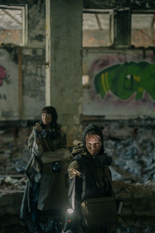 Free Two people exploring a dystopian ruin with graffiti and debris. Stock Photo