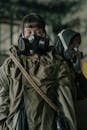 Man in Green Jacket Wearing Black Gas Mask