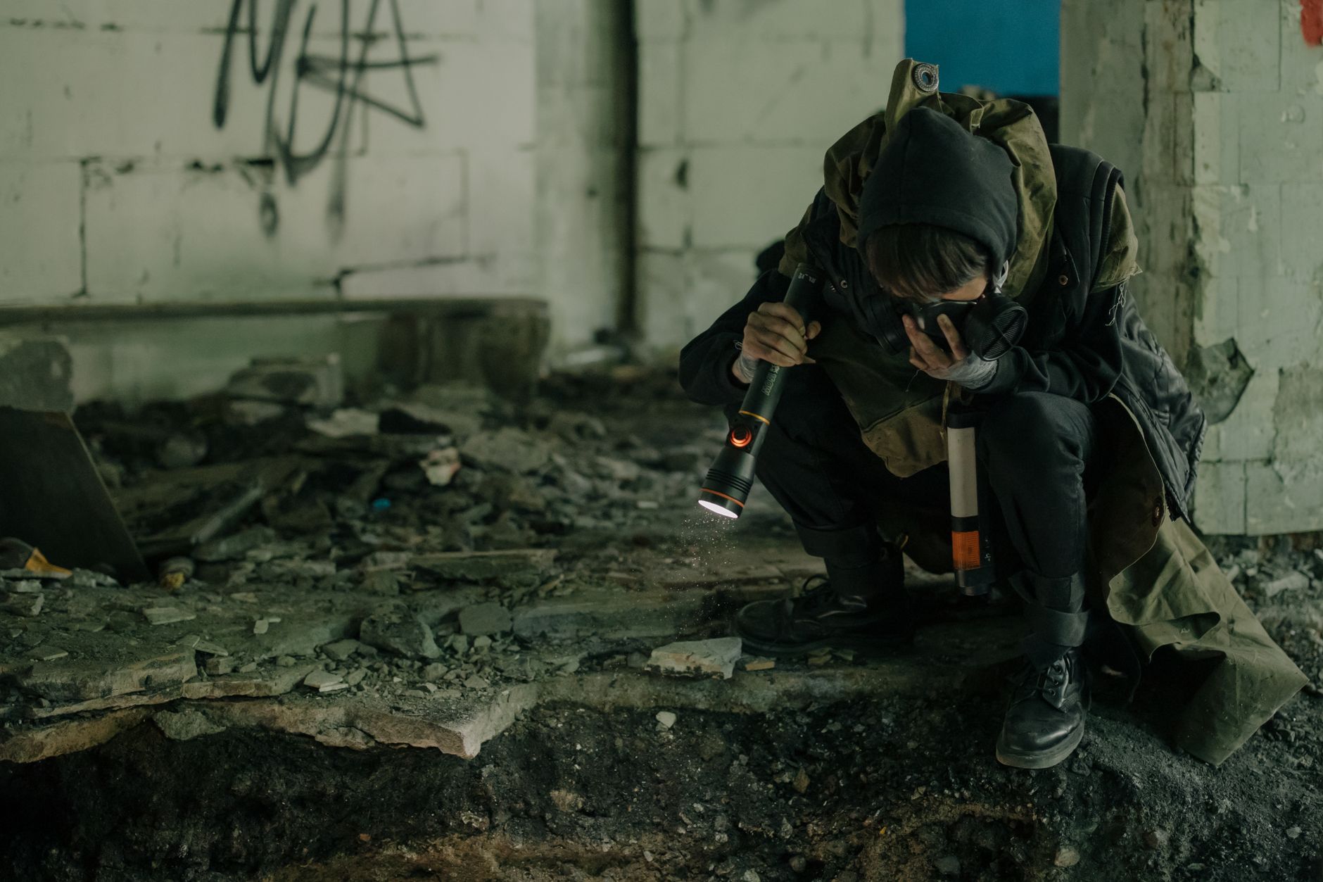 A person explores a dark, abandoned building with a flashlight, signifying survival and exploration.