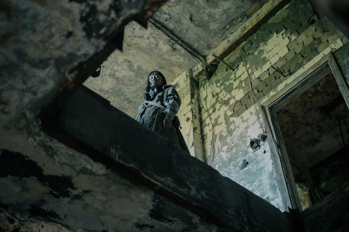 Man in Black Jacket and Pants Sitting on Concrete Wall