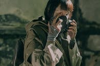 Woman in Green Jacket Covering Face With Black Mask