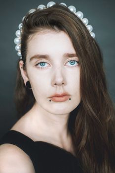 一位头戴珍珠发带、蓝眼睛的女子特写肖像，表情安详而沉思
