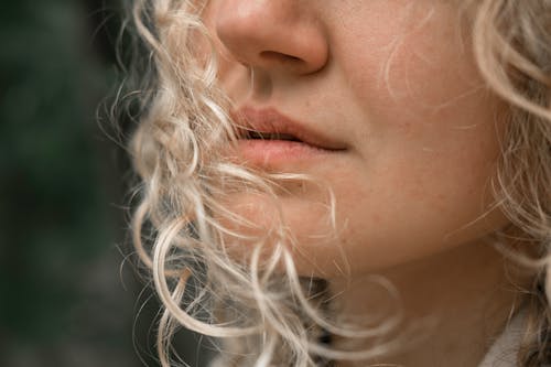 Faceless woman with blond curly hair