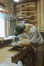 在堆满工具和木板的车间里，工匠从事着木工工作