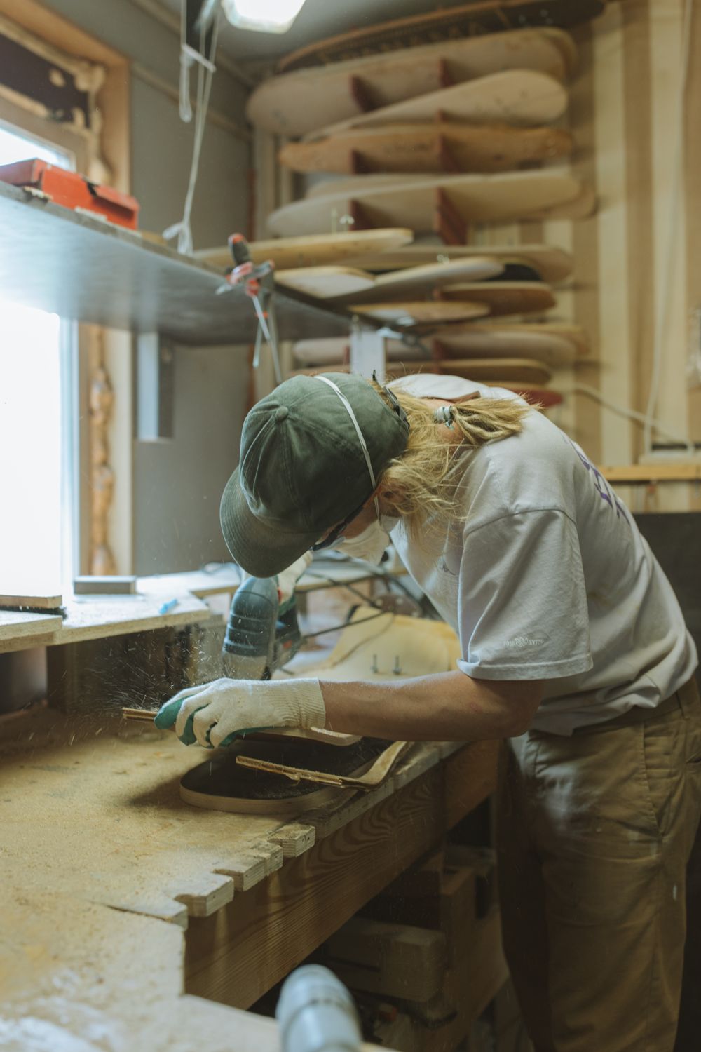 A maker working at a bench in the ABC Widgets workshop, surrounded by tools and stacked timber