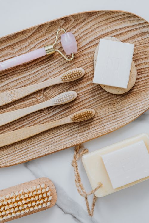 Free Flat lay of eco-friendly bathroom items including toothbrushes, soaps, and facial roller on wooden tray. Stock Photo