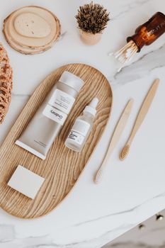 Modern minimalist flat lay featuring sustainable skincare and oral care items on wooden tray.