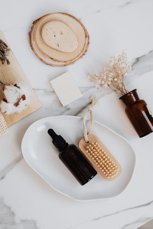 Free Flat lay of eco-friendly skincare products including a serum bottle and facial brushes on a marble surface. Stock Photo