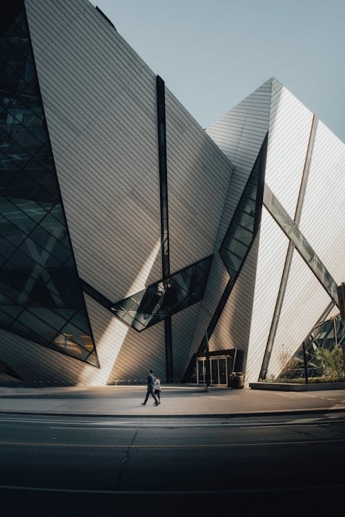 A Couple Walking Beside Gray Concrete Building