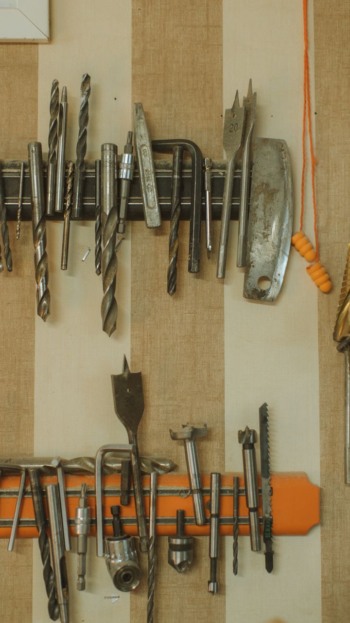 stainless steel magnetic knife strip holding coffee scoops and a frother above a kitchen counter