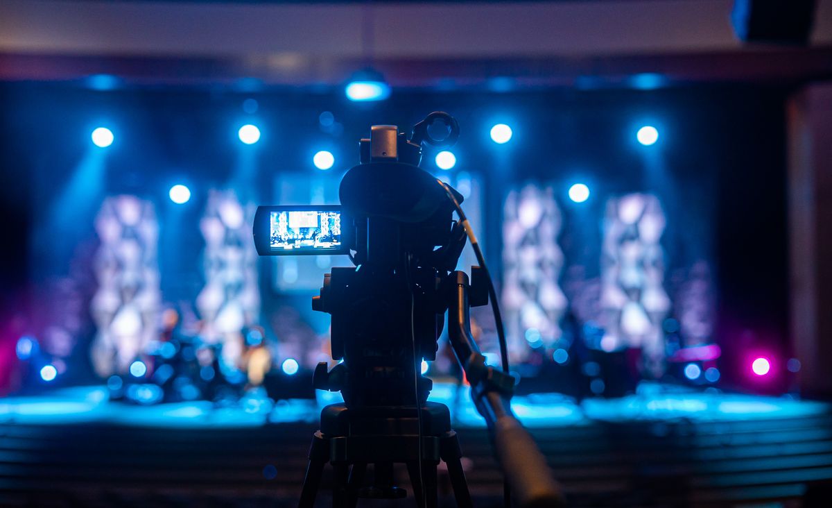 Video camera filming an illuminated event stage