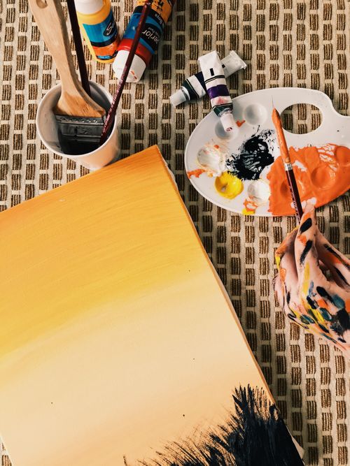 Free A vibrant setup of art supplies with a canvas in progress, featuring paint tubes, brushes, and a palette. Stock Photo