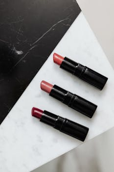 Three lipsticks arranged on a marble surface with a modern contrast, perfect for beauty and fashion themes.