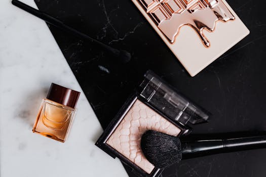 High-angle view of beauty products including eyeshadow, lipstick, and perfume on marble and black backgrounds.