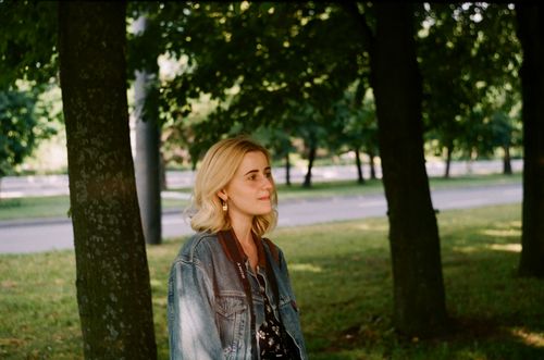 Free Young female photographer in casual clothes with camera strap strolling in park at daytime Stock Photo