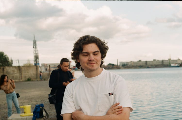 Smiling Young Man With Closed Eyes On Bank Of River