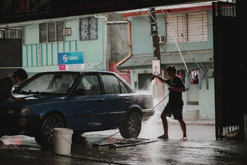 Free Photo of a Man Using a Hose to Wash a Car Stock Photo