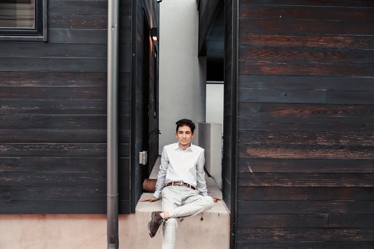 Elegant Ethnic Man Resting On Concrete Curb