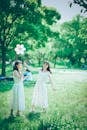 Photo of Women in White Dresses Standing on Green Grass