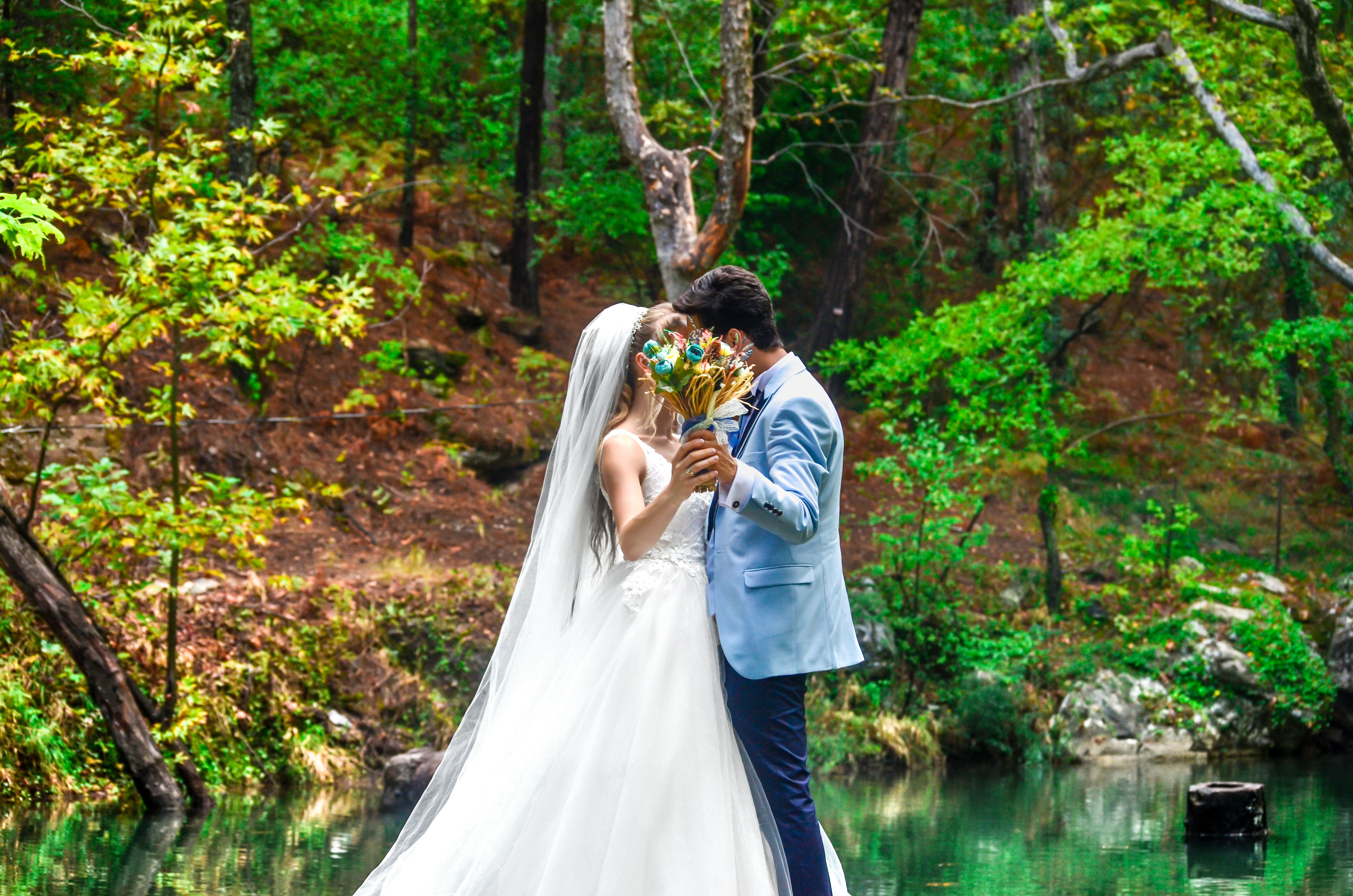 Bride and Groom Covering Their Face With Bouquet of Flowers · Free ...