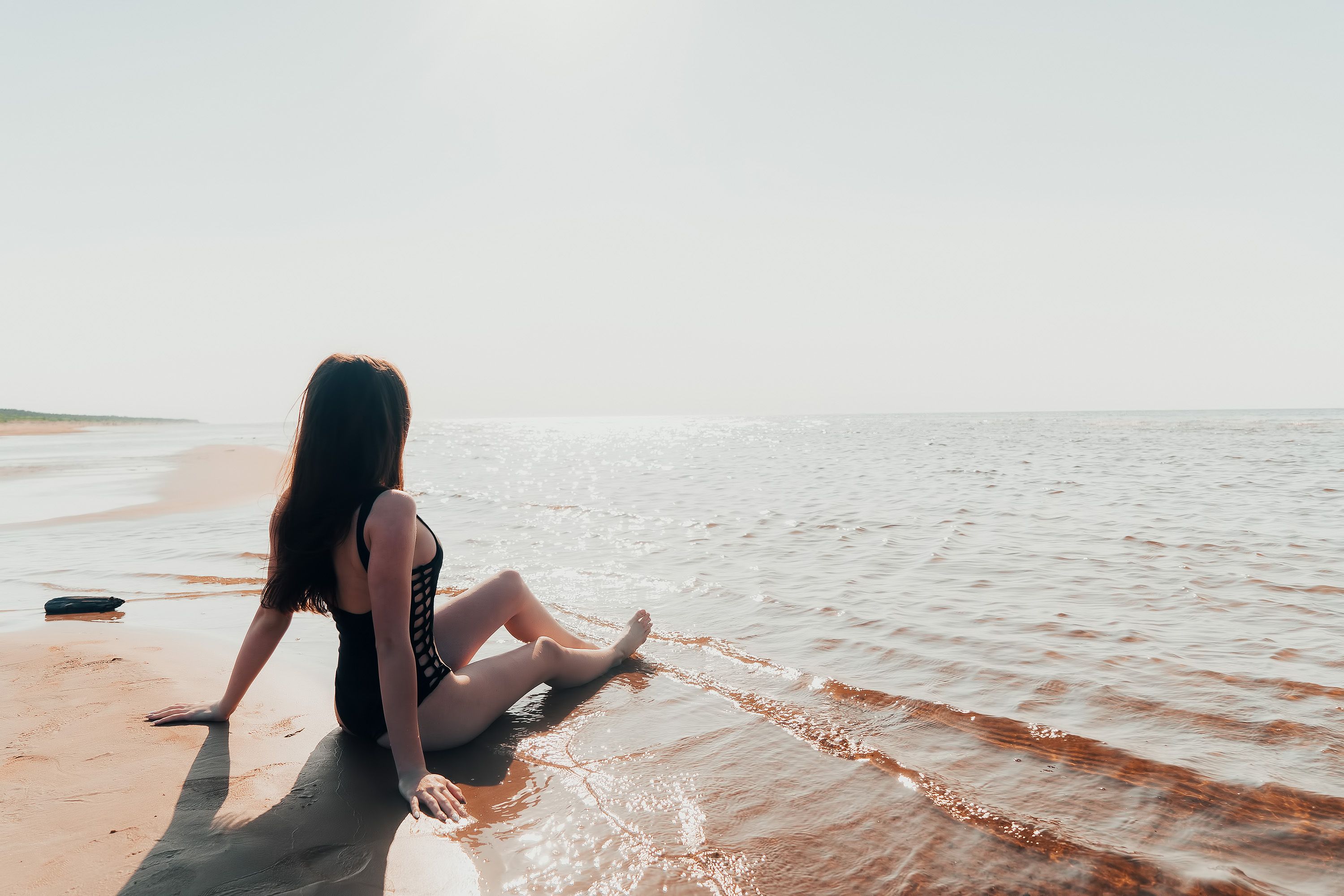 Photo of a Woman in a Black Bikini Sitting on Brown Sand · Free Stock Photo