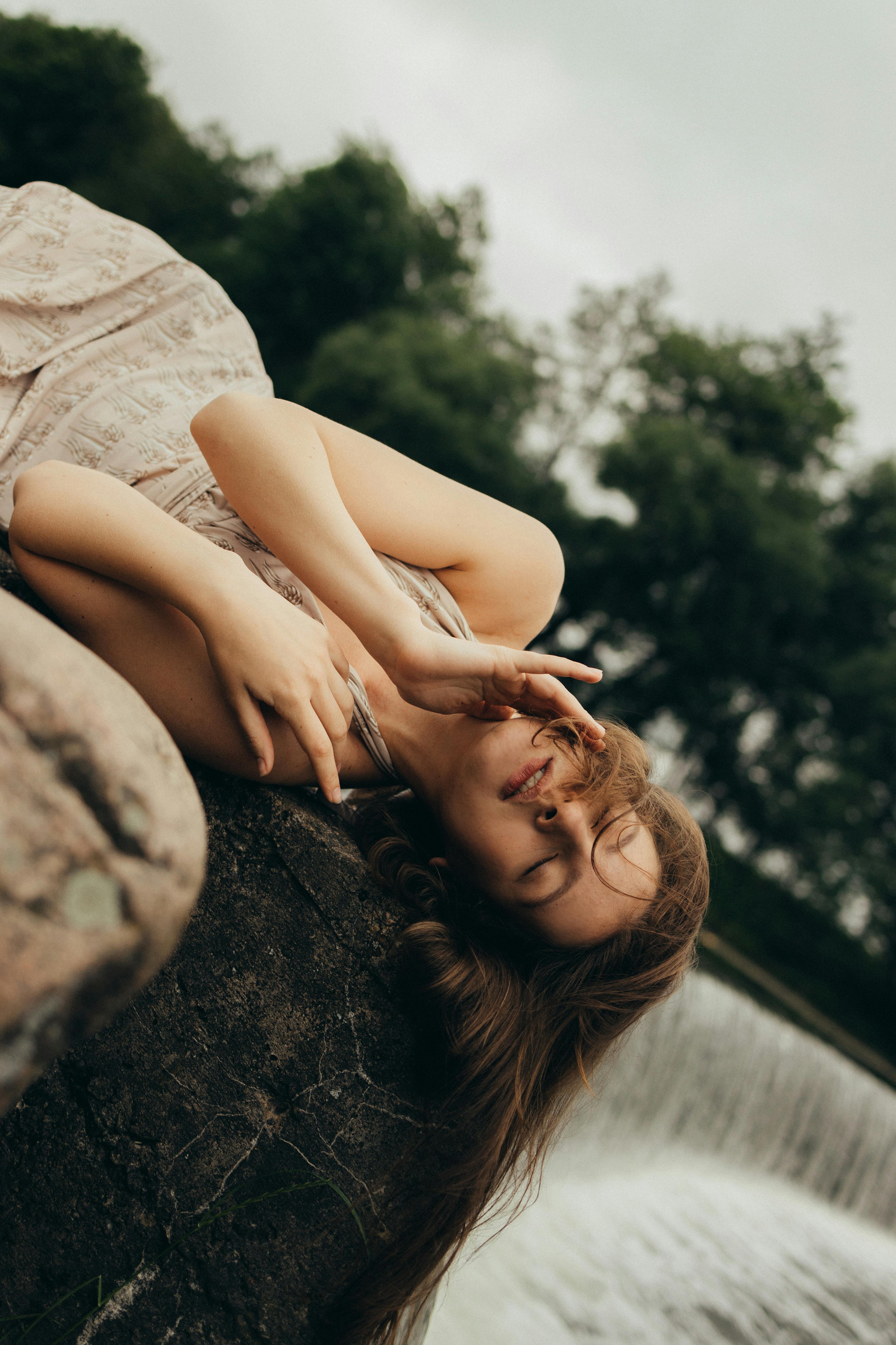 一个女人闭着眼睛，安静地躺在瀑布旁，这宁静的场景体现了平静