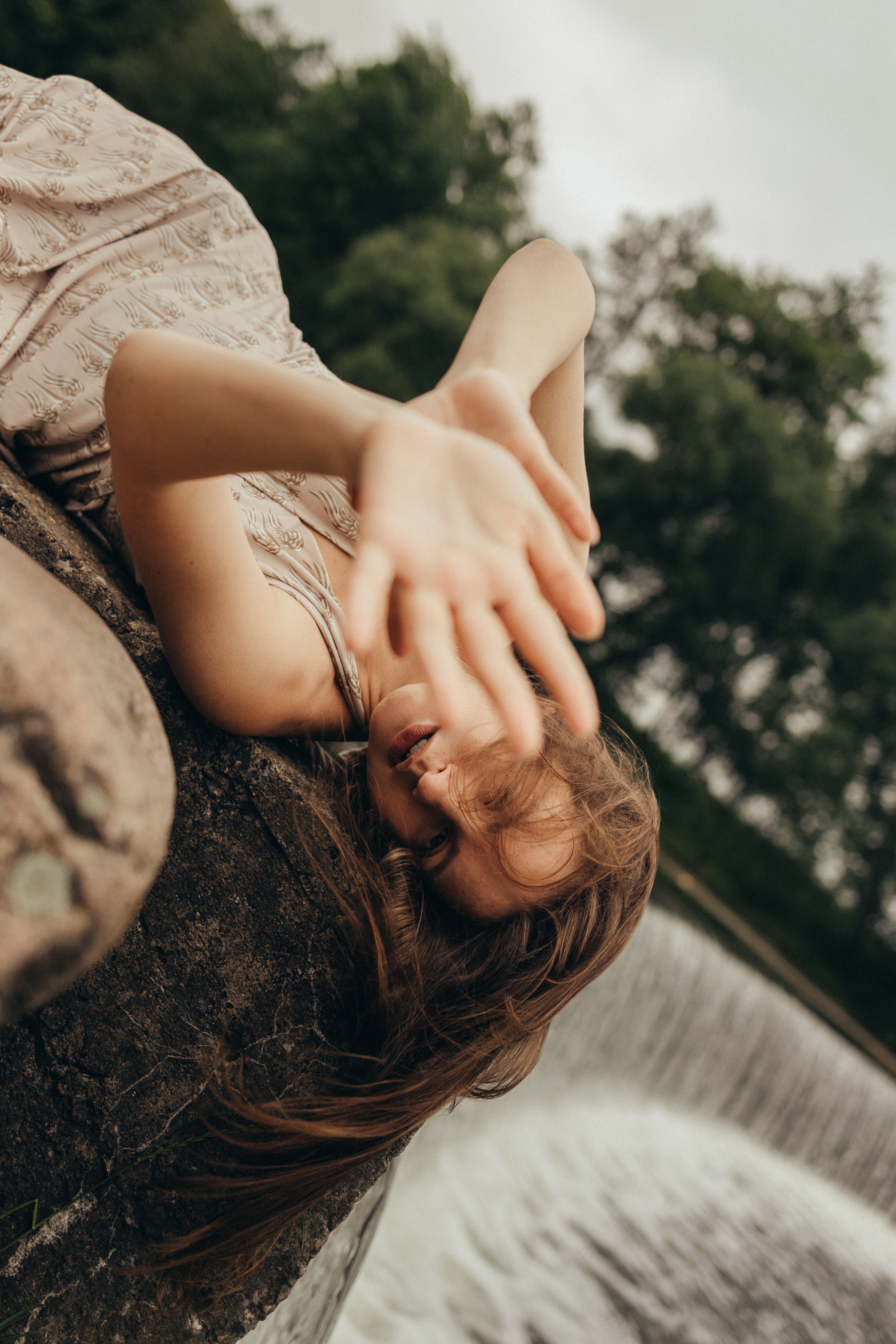 女子用瀑布顽皮地遮住脸，营造出无忧无虑的夏日气息