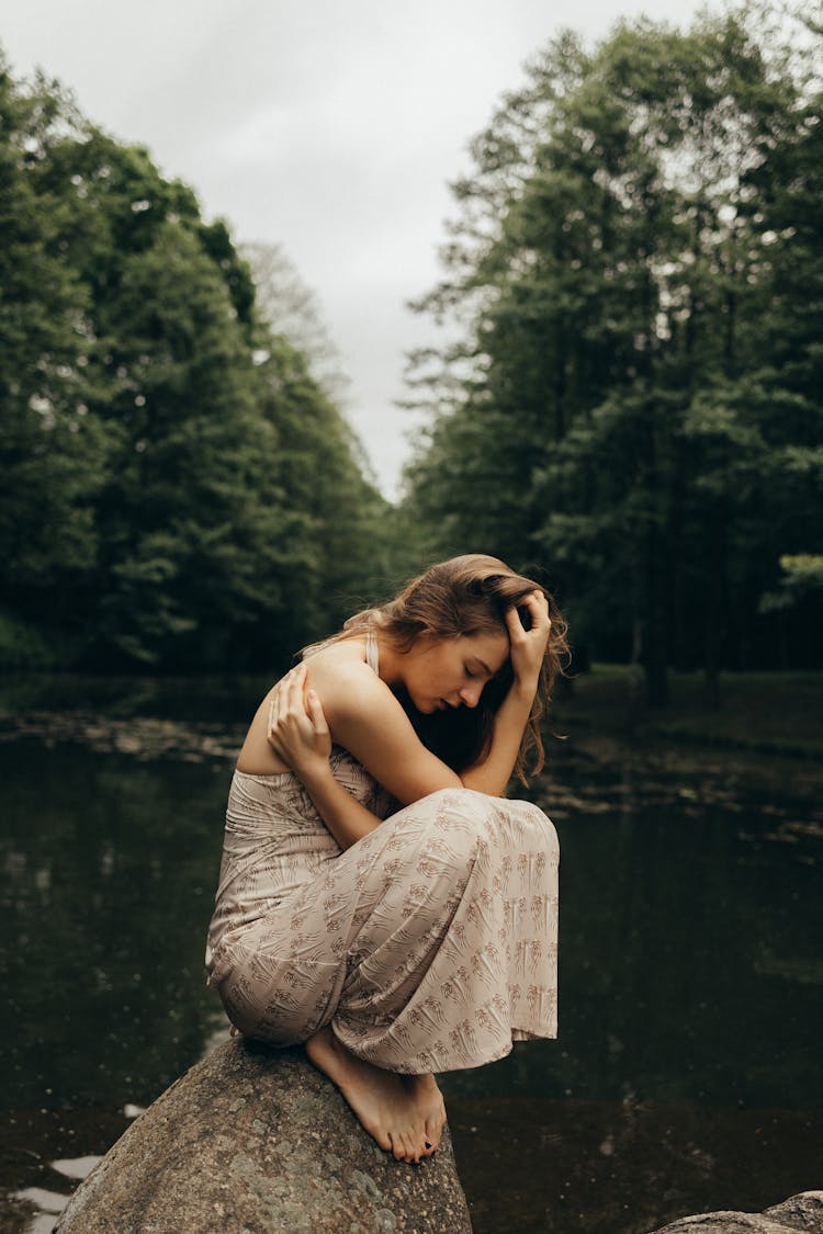 Woman Sitting On A Rock While Her Hand Is On Her Head