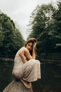 一位身着连衣裙的女子在森林的河边冥想，营造出宁静的氛围
