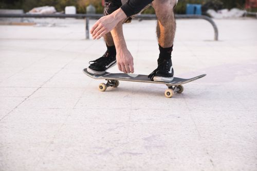 Free Close-up of a skater's legs balancing on a skateboard at an outdoor skate park. Stock Photo