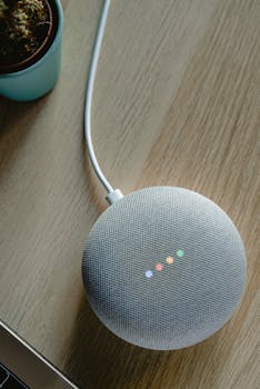 A top view of a smart speaker with a glowing indicator on a desk, emphasizing modern technology.