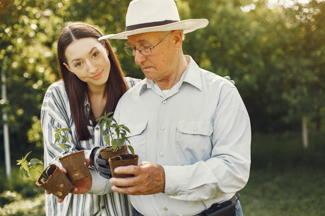 Free Grandfather and His Granddaughter Holding Potted Plants Stock Photo