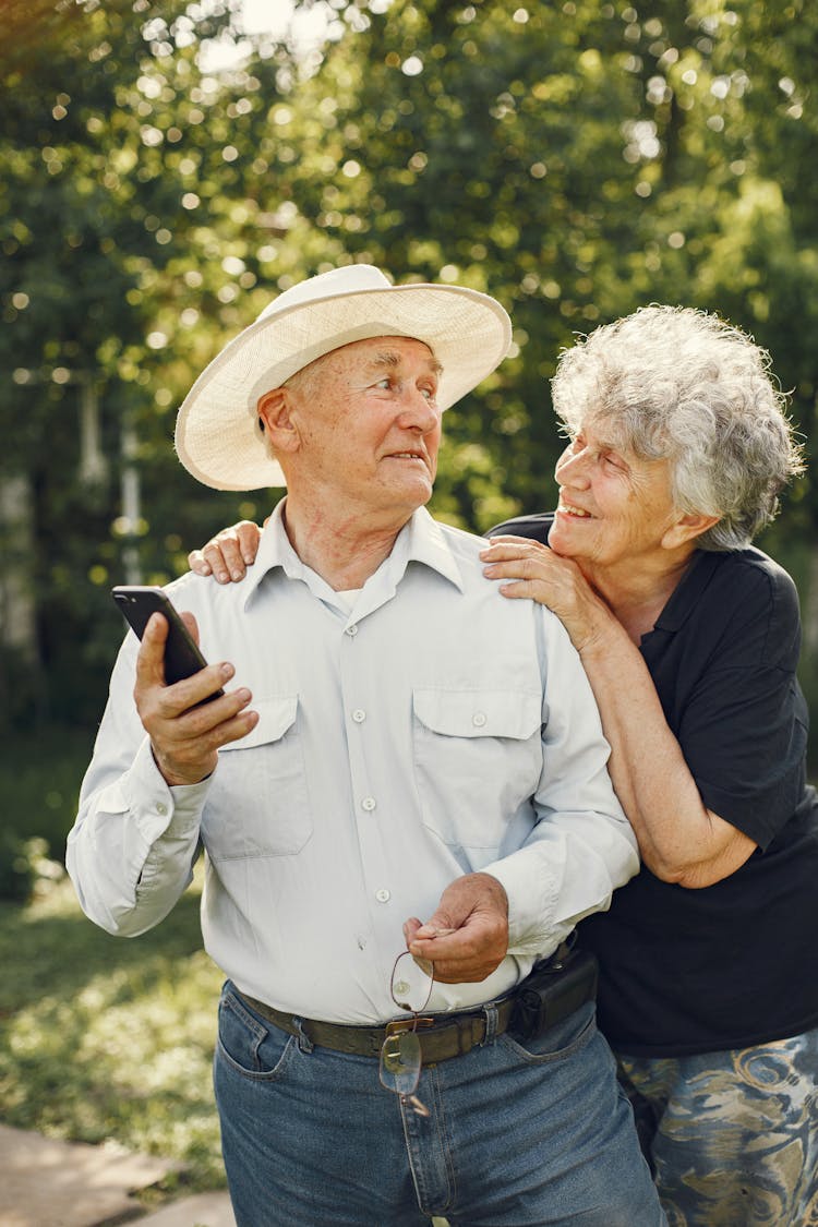 Elderly Couple Enjoying Walk In Sunny Garden