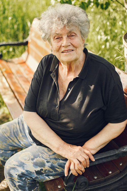 Free Elderly woman enjoying a sunny day outdoors, resting on a bench. Stock Photo