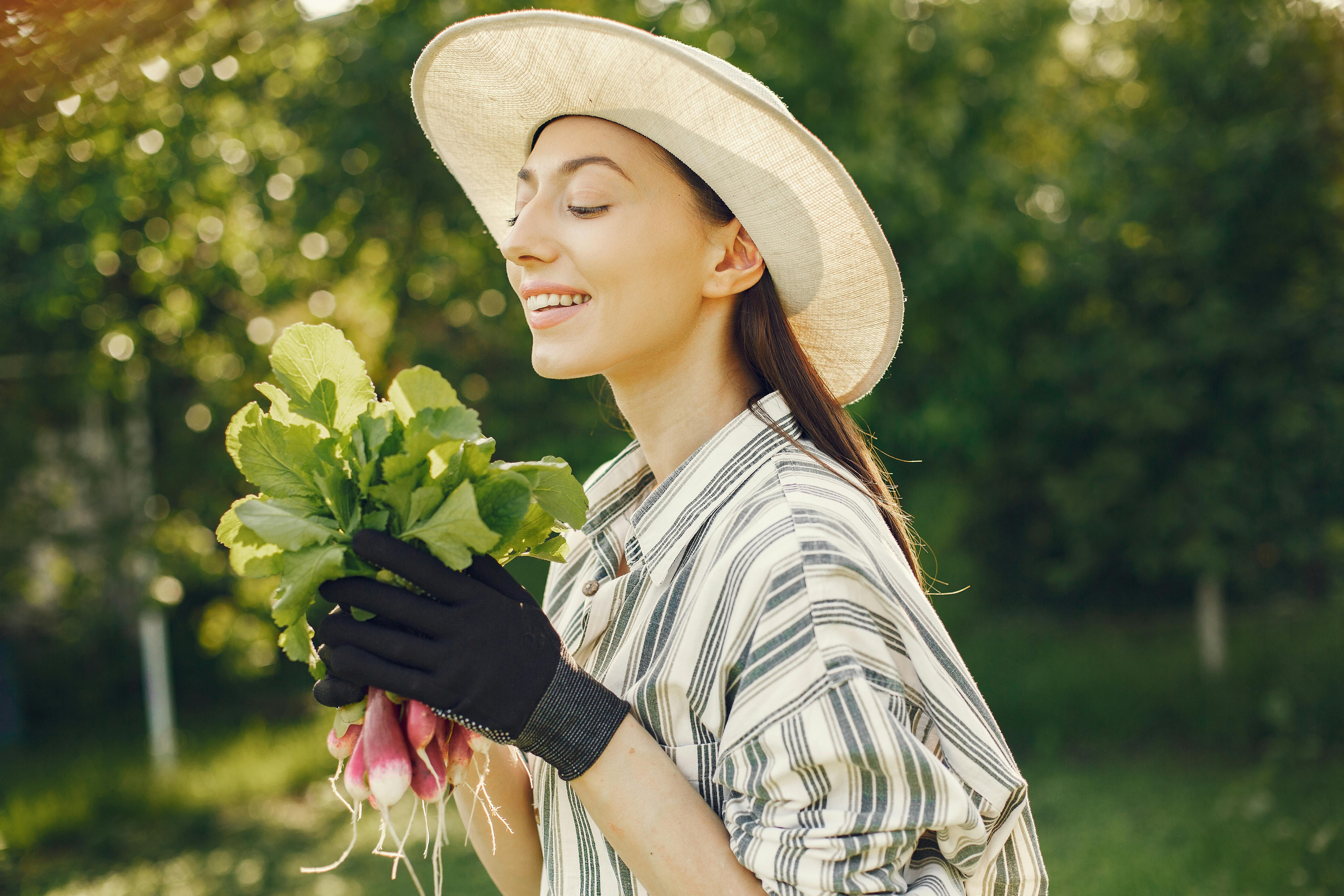 Happy woman enjoying a fresh harvest of radishes in a sunny garden.